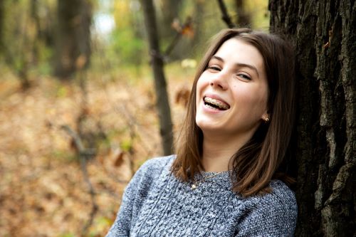 young teenage girl with braces leaning against tree wearing sweater RESIZED